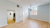Located at 2132–2144 Park St in Columbia, SC, this 1-bedroom, 1-bathroom residence offers a clean, modern aesthetic throughout. Light blue-gray walls and warm light wood-tone flooring run consistently across every room, creating a cohesive and inviting atmosphere.

The open living area benefits from soaring ceilings and a large multi-pane window that draws in generous natural light, complemented by a sleek ceiling fan with a matte black finish. A charming entry door with transom window detail adds architectural character to the space.

The galley-style kitchen is well-equipped with white shaker cabinetry, matte black hardware, a marble-look quartz countertop, a stainless steel undermount sink with a black gooseneck faucet, and a full suite of stainless steel appliances including a refrigerator, range, and over-the-range microwave.

The bedroom is generously sized, featuring multiple windows that frame views of surrounding brick architecture and allow for abundant natural light, along with a ceiling fan and closet access.

The bathroom is finished with white shaker-style cabinetry, a quartz countertop, matte black fixtures, and a full tub-shower combination with clean white surround. Light wood flooring continues seamlessly into the bathroom, tying the overall design together.