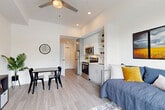 Located at 1900 Bickford Ave in Snohomish, WA, this thoughtfully designed studio unit makes efficient use of its compact footprint across a single floor. The open-concept layout seamlessly integrates the living, dining, and kitchen areas, creating a cohesive and functional living space. Light gray luxury vinyl plank flooring runs throughout, contributing to a clean, modern aesthetic.

The kitchen is outfitted with stainless steel appliances, including a range and microwave, complemented by light gray cabinetry with gold-toned hardware and open shelving for additional storage. A full-size refrigerator and a single-basin sink complete the well-equipped space.

The main living area benefits from a large floor-to-ceiling window that floods the room with natural light and offers views of the surrounding Pacific Northwest landscape. A ceiling fan adds both function and style overhead. There is ample room for a dining table and seating area, making the space versatile for everyday living.

The hallway leads to a full bathroom featuring wood-look tile flooring, a floating vanity with a white countertop, and a shower/tub combination, all finished in a crisp, all-white palette. The overall ambiance of the unit is bright, modern, and efficiently designed to maximize comfort.
