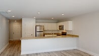 This well-appointed two-story townhome in Columbia, SC offers three bedrooms and two bathrooms across two generously sized floors. The main level features an open-concept kitchen and living area bathed in natural light from large sliding glass doors that open to outdoor views. The kitchen is a standout, showcasing granite countertops, crisp white cabinetry, stainless steel appliances including a refrigerator, microwave, and range, and a peninsula with an integrated sink — ideal for both cooking and casual dining. Light wood-look LVP flooring runs throughout the main level, complementing the clean, neutral palette and recessed lighting overhead. A wide hallway connects the entryway to the living space, with a carpeted staircase leading to the upper floor. Upstairs, three bedrooms offer comfortable retreats, with the spacious primary bedroom featuring a ceiling fan, plush carpet, and direct access to a private bathroom complete with a granite vanity and shower. Additional bedrooms are finished with soft carpet and ample natural light. A dedicated laundry area with washer and dryer hookups and wire shelving adds everyday convenience. The bathrooms maintain the home's cohesive design with granite countertops and light wood-look flooring, creating a polished, move-in-ready finish throughout.