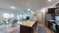 This thoughtfully designed single-floor residence offers a seamless blend of modern finishes and functional living spaces. At the heart of the home, the open-concept kitchen is a standout feature, showcasing rich dark cabinetry, granite-style countertops, stainless steel appliances, and a large center island with built-in sink and pendant lighting overhead — ideal for both meal preparation and casual dining. Wood-look flooring flows throughout the main living areas, adding warmth and continuity.

The adjacent living and dining areas are bright and welcoming, with a ceiling fan, recessed lighting, and windows that invite natural light. The dining space comfortably accommodates a round table with ample room for entertaining.

The bedrooms offer plush carpeting and generous natural light. One bedroom serves as a versatile home office, featuring wood flooring, large windows with decorative curtains, and a frosted-glass door for privacy.

The bathroom is clean and well-finished, with wood-look flooring, a tub-shower combination with tiled surround, and dark vanity cabinetry that ties in with the kitchen aesthetic.

Throughout the space, a consistent design language of dark cabinetry, neutral walls, and warm flooring creates a cohesive and inviting atmosphere suited for comfortable everyday living.