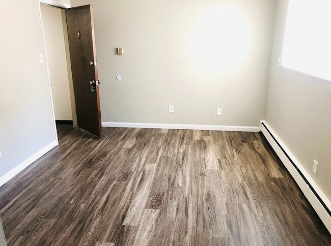 Inviting room with elegant wood flooring, abundant natural light, and freshly painted walls, perfect for a cozy living space. - Prentice Place
