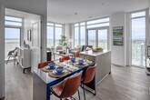 Located on the 30th floor at 22 Hughson Street in downtown Hamilton, this contemporary unit offers a thoughtfully designed layout across a single level, incorporating a bedroom, two bathrooms, a dedicated office, and an open-concept kitchen, dining, and living area. Light hardwood flooring runs throughout, complemented by crisp white walls and recessed lighting that lend the space a clean, modern aesthetic. The kitchen features stainless steel appliances, two-tone cabinetry with warm wood accents, a white tile backsplash, and a central island with seating — ideal for casual dining. Floor-to-ceiling windows in both the living area and the office flood the space with natural light and frame expansive panoramic views of Hamilton's skyline, surrounding cityscape, and Lake Ontario. The living room opens directly to a private balcony through sliding glass doors. The primary bedroom is generously sized, featuring a full-height upholstered accent wall, mirrored sliding closet doors, and balcony access with stunning lake views. Both bathrooms are finished with large-format marble-style tile, including a soaker tub with shower in the main bath. The dedicated office, bathed in natural light from oversized windows, provides an ideal workspace with commanding city views.