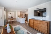 Located in the coastal city of San Clemente, California, this single-floor residence offers a bright, well-designed layout with a welcoming coastal ambiance throughout. Light wood-style flooring runs continuously across the main living areas, complemented by crown molding, recessed lighting, and textured ceilings that add character to every room.

The open-concept living area is generously sized, featuring large windows and a sliding glass door that lead to a private balcony, filling the space with natural light and providing outdoor access. The adjacent dining area is a cozy nook framed by windows, while the kitchen features white shaker cabinetry, white quartz countertops, stainless steel appliances, and a peninsula that connects seamlessly to the living and dining spaces.

The two bedrooms are comfortably proportioned, each equipped with ceiling fans, large windows that invite natural light, and easy access to closet storage. The primary bedroom includes an en-suite bathroom with a white vanity, undermount sink, and a tub-shower combination. A second full bathroom features a clean white vanity with ample counter space and a shower-tub combo.

A closet near the entry provides additional storage. The unit's neutral palette and abundant natural light create a relaxed, airy atmosphere well-suited to Southern California coastal living.