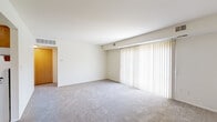 This single-floor unit offers a practical and well-organized layout designed for comfortable everyday living. The living area is the centerpiece of the space, featuring plush wall-to-wall carpeting and a large sliding glass door dressed with vertical blinds, providing direct access to a private balcony and framing views of surrounding greenery. The open sightlines and neutral cream-toned walls create a bright, airy atmosphere throughout.

The galley-style kitchen is efficiently arranged with warm oak cabinetry lining both sides, offering ample upper and lower storage. White appliances, including a coil-top electric range, refrigerator, and dishwasher, are included alongside light-toned countertops and a stainless steel sink. The kitchen flows naturally into the entry and living areas via tile flooring, providing a clear transition between spaces.

The bedrooms are generously proportioned, each finished with soft carpeting and windows fitted with vertical blinds that allow natural light while maintaining privacy. Views of mature trees outside add a pleasant natural element to the rooms.

The full bathroom is cleanly finished with a tiled tub-and-shower combination, a wood-toned vanity with ample storage, a large mirror, and tile flooring, delivering a functional and tidy design. Overall, the unit maintains a consistent, neutral aesthetic throughout.