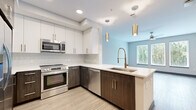 Located on Charlotte Avenue in Nashville's vibrant West End corridor, this 2-bedroom, 2-bathroom residence offers a well-designed, single-level layout with contemporary finishes throughout. The open-concept kitchen is a standout feature, showcasing two-tone cabinetry with white uppers and dark wood lowers, quartz countertops, a large undermount sink, stainless steel appliances including a French door refrigerator, electric range, microwave, and dishwasher, and gold pendant lighting that adds warmth to the space. Light wood-style flooring extends through the main living areas, creating a cohesive and modern aesthetic. Both bedrooms are generously proportioned, each featuring plush carpeting, ceiling fans, and a trio of tall windows that invite abundant natural light and offer leafy outdoor views. The two bathrooms are finished with matching dark wood vanities, quartz countertops, undermount sinks with brushed nickel fixtures, large framed mirrors, and marble-tiled walk-in showers. Light wood-style tile flooring completes the clean, modern look. Additional highlights include two closets, a dedicated hallway, and recessed lighting throughout. The neutral color palette and quality finishes create a bright, move-in-ready environment.