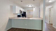 This premium renovated Belgian floor plan offers two bedrooms and two bathrooms across a thoughtfully designed single-story layout. The kitchen serves as a focal point, featuring white shaker cabinetry, light countertops, and a full suite of stainless steel appliances, including a range, microwave, dishwasher, and refrigerator. Pendant lighting above the peninsula adds a modern touch, while wood-look flooring ties the space together seamlessly.

The living area is highlighted by a corner fireplace and vaulted ceilings that lend a sense of openness, complemented by the same warm wood-look flooring. Both bedrooms are generously sized, carpeted for comfort, and receive natural light through large multi-pane windows with outdoor views. Each bedroom includes closet space, with one bedroom offering direct access to its own bathroom.

The two bathrooms mirror each other in style, each featuring white vanity cabinetry, a framed mirror, and wood-look flooring. One bathroom includes a glass-enclosed walk-in shower, while the other offers a full tub-shower combination, both accented with decorative tile detailing. The overall aesthetic is clean, bright, and move-in ready.