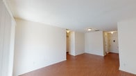 This single-floor residence offers a practical and well-organized layout with consistent warm-toned hardwood-style flooring running throughout the entire space. The open living area serves as the heart of the home, bathed in natural light from a sliding glass door fitted with vertical blinds that lead to an outdoor area. A textured ceiling and flush-mount light fixtures provide a clean, understated finish to the living space.

The galley-style kitchen is efficiently designed with white cabinetry on both sides, light granite-patterned countertops, a double stainless steel sink, and white appliances including a refrigerator and stovetop range. A window above the sink allows for natural light and ventilation.

The two bedrooms are comfortably sized, each featuring windows with horizontal blinds that invite natural light while maintaining privacy. One bedroom includes a sliding-door closet offering convenient built-in storage. Both rooms share the same warm flooring and neutral wall tones found throughout the residence.

The full bathroom is neatly appointed with a white vanity, single-basin sink, a wall mirror, and a combined bathtub and shower unit, all finished in clean white tones. The overall ambiance of the space is bright, neutral, and move-in ready, offering a functional and cohesive living environment.