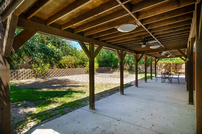Covered patio with three outdoor ceiling fans. - 7701 Maestro Ave