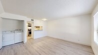 This efficient and thoughtfully designed 1-bedroom, 1-bathroom residence is laid out on a single floor, offering a clean and functional living environment. Light wood-style flooring runs throughout the unit, complementing the bright white walls and textured ceilings to create a fresh, airy atmosphere.

The open living room provides a comfortable gathering space and connects seamlessly to the kitchen via a pass-through counter. The kitchen is well-equipped with stainless steel appliances — including an electric range, dishwasher, and refrigerator — paired with gray shaker-style cabinetry and light granite-look countertops, offering both style and practicality. In-unit laundry is conveniently located adjacent to the kitchen area.

The bedroom is a well-proportioned retreat, featuring a large sliding-door closet and a window that invites natural light into the space. Clean white walls and consistent flooring maintain the cohesive design throughout.

The bathroom is neatly appointed with a combined shower and tub, a dark-toned vanity with a granite-style countertop and single sink, and brushed nickel fixtures that add a polished finishing touch. A hallway connects the rooms efficiently, completing this compact yet functional floor plan.