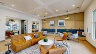 Located at 2045 Paseo Belluno in Chula Vista, CA, this thoughtfully designed single-floor space combines modern aesthetics with functional versatility. The living room serves as the heart of the space, featuring shiplap-style ceiling detailing, recessed lighting, and large glass doors that invite an abundance of natural light and outdoor views. Rich cognac leather seating, a geometric patterned area rug, and a sculptural round coffee table create a warm, inviting atmosphere. A built-in teal banquette runs along a paneled wood-accent wall, complemented by pendant lighting and framed landscape artwork, offering additional lounge and social seating. A dark wood reception console anchors the entry area, adding contrast to the light tile flooring throughout. The dining room is an intimate setting featuring a round marble-top table, leather side chairs, and an exposed white brick accent wall adorned with bold abstract artwork. The office is a dedicated conference room with a rectangular wood table, leather chairs, a mounted display screen, and the same white brick wall treatment, providing a polished and productive environment. Together, these spaces offer a refined, cohesive design ideal for community gathering and focused work.