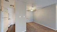 This single-story 2-bedroom, 1-bathroom unit offers a practical and well-organized layout across a comfortable footprint. The living room is an open, carpeted space bathed in natural light through a sliding glass door fitted with vertical blinds, which also provides direct patio access. Neutral gray walls and a textured ceiling carry throughout the unit, lending a consistent and clean aesthetic.

The galley-style kitchen features wood-look flooring, white cabinetry with ample overhead and base storage, a speckled laminate countertop, a double stainless steel sink, and white appliances including a range and refrigerator. Adjacent to the kitchen, a hallway connects the main living areas to the bedrooms and bathroom.

The primary bedroom is a generously sized, carpeted room equipped with a ceiling fan with light fixture and a dedicated closet. The second bedroom is similarly appointed with carpet, a ceiling fan, and a window for natural light. Both rooms are finished with the same neutral palette seen throughout the unit.

The bathroom features wood-look flooring, a single-sink vanity with a speckled countertop and white cabinetry, a full tub-shower combination, and a toilet — all finished in clean white tones. A dedicated closet provides additional storage within the unit.