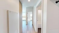 This well-appointed 2-bedroom, 2-bathroom unit in Calgary, AB offers a thoughtfully designed open-concept layout finished with contemporary materials throughout. Light-toned hardwood flooring flows seamlessly across the entire living space, complementing the clean white walls and modern aesthetic.

The kitchen serves as a central focal point, featuring warm wood cabinetry, dark stone countertops, a subway tile backsplash, stainless steel appliances, and a kitchen island with an integrated dining extension — ideal for casual meals or entertaining. Recessed and pendant lighting add a refined touch overhead.

The living area is bright and airy, anchored by expansive floor-to-ceiling windows that frame views of Calgary's treetops and cityscape, filling the space with abundant natural light.

Both bedrooms are finished with the same light hardwood flooring and feature large windows with outdoor views and sliding-door closets for efficient storage. The primary bedroom benefits from its own ensuite bathroom, complete with a sliding glass-door shower, dark tile flooring, a wood-tone vanity, and a dark stone countertop. The second bathroom includes a full soaker tub with a tiled surround and modern chrome fixtures.

A hallway with wood-panel built-in storage connects the rooms, contributing to the unit's clean, functional design.