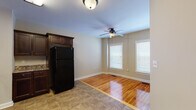 This single-floor space is thoughtfully laid out, offering a well-connected series of rooms finished with consistent, warm-toned materials throughout. Polished hardwood flooring extends across the living and bedroom areas, reflecting natural light and contributing to a bright, inviting atmosphere. Neutral beige walls provide a clean backdrop throughout, complemented by white trim and baseboards.

The kitchen is well-appointed with rich, dark wood cabinetry extending to the ceiling, granite-style countertops, and a full suite of black appliances including a refrigerator, electric range with overhead microwave, and dishwasher. Tile flooring in the kitchen provides a practical transition from the hardwood in the adjacent dining area, which is brightened by two windows and features a ceiling fan overhead.

The bedrooms are generously sized, each fitted with ceiling fans and windows dressed with white blinds that allow ample natural light. The rooms connect via a hallway, offering a functional flow throughout the unit.

Two bathrooms serve the space. One features classic white subway tile wainscoting, a mosaic tile floor, a vanity with dark wood cabinetry, and a window for natural light. The second is a more compact restroom with tile flooring and a frosted window. Together, these bathrooms offer practical and well-finished facilities for daily use.