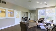 Located at 2979 Green Arbor Ln in Dublin, Ohio, this single-floor space functions as a professional office or leasing center designed to accommodate both staff and visitors with ease. The interior is finished in warm neutral tones, with taupe-painted walls and white trim that create a clean, inviting atmosphere throughout.

The main area features a comfortable seating arrangement with plush upholstered armchairs and a small round side table, providing a welcoming space for guests. A dedicated workstation alcove is built into the wall and equipped with a desktop computer setup and sleek modern chairs, offering a functional workspace for staff. Recessed lighting in the ceiling ensures consistent, well-distributed illumination across the room.

Multiple white-paneled doors provide access to adjoining spaces, while large windows along the perimeter allow natural light to flow generously into the interior, enhancing the open and airy feel of the space. The flooring transitions between carpet in the seating area and hard flooring near the entrance, offering both comfort and practicality.

Overall, this space strikes a balance between professional functionality and approachable comfort, making it well-suited for client-facing operations such as a leasing office or administrative hub.