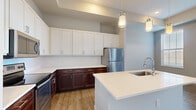 Located at 6770 Printers Blvd in New Albany, Ohio, this well-appointed one-bedroom, one-bathroom residence offers a thoughtfully designed single-floor layout with a cohesive blend of modern finishes throughout. The open-concept kitchen and living area serves as the heart of the home, featuring a striking two-tone cabinet design with rich dark lower cabinets and crisp white upper cabinetry that extends to the ceiling for generous storage. Stainless steel appliances, white quartz countertops, and a peninsula island with an undermount sink and pendant lighting complete the kitchen's contemporary aesthetic. Warm hardwood-style flooring runs through the main living and kitchen areas, adding both style and durability. The bedroom is a comfortable retreat with plush carpeting, neutral tones, and multiple windows that allow ample natural light to fill the room. A walk-in closet outfitted with wire shelving systems provides well-organized storage capacity. The bathroom features a clean, modern vanity with white shaker-style cabinetry, quartz countertops, a large mirror, and stylish lighting fixtures. Soft, neutral wall colors and consistent white trim throughout the space create a calm, cohesive ambiance well-suited for everyday living.