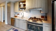 Located at 1000 Lake St in Oak Park, Illinois, this thoughtfully designed studio unit offers a seamless blend of modern aesthetics and functional living. The open-concept layout combines the sleeping and living areas into a single, cohesive space, featuring light wood-tone flooring that runs throughout and clean white walls that enhance the sense of openness. Large floor-to-ceiling windows flood the room with natural light and frame elevated views of the surrounding Oak Park landscape, creating a bright and airy atmosphere. A sliding closet provides convenient built-in storage within the main living area. The kitchen is outfitted with light wood cabinetry, open shelving, quartz countertops, and a striking chevron-patterned tile backsplash. Stainless steel appliances — including a gas range and dishwasher — complete the well-equipped culinary space. The bathroom offers a clean, contemporary design with large-format tile flooring, a wood-tone vanity with an integrated sink, a framed mirror, and modern lighting fixtures. The overall ambiance of the unit is calm and contemporary, with a neutral color palette and quality finishes that reflect the modern character of this Oak Park address.