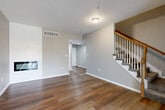 Located at 5337 Millbrook St in Shawnee, KS, this multi-story home spans three floors and offers a thoughtfully designed layout with 2 bedrooms and 4 bathrooms. The main living area features rich hardwood-style flooring, neutral gray walls, and a striking shiplap-accented fireplace that serves as a focal point of the room. A staircase with a warm wood handrail and classic white balusters connects the floors, adding architectural charm. The kitchen is well-appointed with warm honey-toned cabinetry, stainless steel appliances including a refrigerator, range, microwave, and dishwasher, complemented by light countertops and hardwood-style flooring that continues from the adjoining living space. A hallway connects the main areas seamlessly, with access to the lower level. The spacious primary bedroom is a standout, featuring vaulted ceilings, a ceiling fan, plush carpeting, and a natural light-filled window. It also includes a walk-in closet with wire shelving for ample storage. The bathrooms are finished with tile flooring and tub-shower combinations. A dedicated utility room adds practical functionality. Each floor offers its own distinct footprint, providing comfortable separation of living, sleeping, and utility spaces throughout the home.