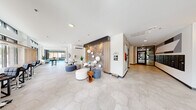 Located at 3725 N 27th St in Tacoma, Washington, this single-floor lobby space offers a thoughtfully designed, contemporary environment that balances aesthetic appeal with practical functionality. The expansive open-plan layout is finished with large-format hexagonal tile flooring throughout, creating a cohesive and polished foundation.

A dramatic focal point in the central lounge area features a backlit exposed brick accent wall framed by warm wood paneling, adorned with sculptural white spherical fixtures that add a playful artistic touch. Nearby, a floor-to-ceiling marble-clad fireplace surround anchors a comfortable seating area outfitted with teal mid-century-modern lounge chairs, a dark wood coffee table, and an eye-catching chandelier above.

Generous floor-to-ceiling windows along the perimeter flood the space with natural light and provide clear views of the surrounding streetscape, enhancing the open and airy ambiance. Multiple seating vignettes are arranged throughout, offering flexible gathering and relaxation areas. Colorful contemporary artwork is displayed on the walls, contributing to the vibrant yet refined atmosphere.

A private office space features carpeted flooring, a full workstation setup, climate control, and bold abstract art. Additional amenities include elevator access, glass-paneled entry doors with direct access to parking, and curated tropical greenery that adds life and warmth throughout the space.