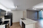 Located on Jasper Avenue NW in Edmonton, Alberta, this 2-bedroom, 2-bathroom unit offers a thoughtfully designed open-concept layout finished with consistent wood-look flooring throughout. The combined living, dining, and kitchen area forms the heart of the unit, anchored by a central kitchen island topped with granite countertops and an undermount double sink. White cabinetry, a subway tile backsplash, and black stainless steel appliances — including a refrigerator, range, built-in microwave, and dishwasher — complete the kitchen. Track lighting illuminates the kitchen and living areas, while a ceiling fan adds comfort to the living space, which benefits from floor-to-ceiling windows that invite natural light and exterior views. Both bedrooms are generously proportioned, each featuring ceiling fans and wood-look flooring. The primary bedroom is notably spacious and includes access to a walk-in closet. The unit offers two full bathrooms, each finished with granite-topped vanities, undermount sinks, and tub-shower combinations. Five closets throughout provide ample storage. An in-unit laundry area adds everyday convenience, rounding out a practical and modern living space.