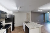 Located on Jasper Avenue NW in Edmonton, Alberta, this 2-bedroom, 2-bathroom unit offers a thoughtfully designed open-concept layout finished with consistent wood-look flooring throughout. The combined living, dining, and kitchen area forms the heart of the unit, anchored by a central kitchen island topped with granite countertops and an undermount double sink. White cabinetry, a subway tile backsplash, and black stainless steel appliances — including a refrigerator, range, built-in microwave, and dishwasher — complete the kitchen. Track lighting illuminates the kitchen and living areas, while a ceiling fan adds comfort to the living space, which benefits from floor-to-ceiling windows that invite natural light and exterior views. Both bedrooms are generously proportioned, each featuring ceiling fans and wood-look flooring. The primary bedroom is notably spacious and includes access to a walk-in closet. The unit offers two full bathrooms, each finished with granite-topped vanities, undermount sinks, and tub-shower combinations. Five closets throughout provide ample storage. An in-unit laundry area adds everyday convenience, rounding out a practical and modern living space.