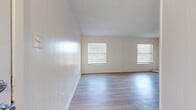 This single-story residence in Hewitt, Texas offers a well-organized 1-bedroom, 1-bathroom layout designed for comfortable everyday living. The open living room is bright and airy, featuring light gray wood-look flooring, white panel-style accent walls, and multiple windows fitted with horizontal blinds that allow natural light to fill the space generously.

The kitchen connects directly to the living area via a raised breakfast bar countertop with a granite-style surface, white cabinetry, and a range hood overhead — a practical pass-through design that keeps the common areas open and connected.

The spacious primary bedroom is carpeted for comfort and includes a ceiling fan with light fixture, a natural light window, and ample room for furnishings. Three closets throughout the unit provide generous storage options.

A hallway connects the main living spaces to the bedroom and bathroom. The bathroom is cleanly finished with a tub-shower combination, a toilet, and a straightforward, functional layout.

Throughout the residence, textured ceilings, clean white walls, and a neutral color palette create a consistent and easy-to-personalize aesthetic. The mix of wood-look flooring in the living areas and carpet in the bedroom adds both practicality and warmth to this efficient Hewitt home.
