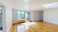 Located at 6001 Chemin de la Côte-Saint-Luc in the sought-after borough of Hampstead, Quebec, this well-maintained 2-bedroom, 1-bathroom unit offers a comfortable and functional single-floor layout. Throughout the main living areas and bedrooms, warm-toned hardwood flooring adds a timeless character and visual continuity to the space.

The living room is bright and open, featuring clean white walls and a simple, uncluttered design that allows for versatile furniture arrangements. A hallway connects the living area to the rest of the unit seamlessly.

The primary bedroom is generously sized, bathed in natural light from a large window, and includes a built-in closet. It also features direct access to a private balcony with an outdoor view of the surrounding neighbourhood. The second bedroom is similarly well-lit, with a sizeable window and a baseboard heating unit, making it a comfortable and practical space.

The kitchen is efficiently laid out in an L-shape, offering ample white cabinetry, warm-toned countertops, a gas range, and a window that brings in natural light. Light wood-style flooring and overhead lighting complete the functional design.

The bathroom is finished with white ceramic wall tiles accented by decorative diamond insets, and includes a full-sized bathtub, a vanity with storage, and a small window for ventilation. Additional built-in cabinetry in a utility area provides convenient extra storage.