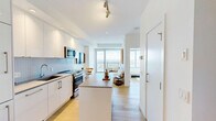 Located in the heart of downtown Edmonton at 10310 102 St NW, this thoughtfully designed one-bedroom, two-bathroom high-rise unit offers a compelling blend of modern finishes and sweeping city views. The open-plan kitchen and living area forms the core of the space, bathed in natural light from large floor-to-ceiling windows that frame breathtaking panoramic views of Edmonton's skyline and beyond. The kitchen is outfitted with sleek, high-gloss white cabinetry, a mosaic tile backsplash, stainless steel appliances including a gas range and built-in microwave, and a movable island with a quartz-style countertop — providing both functionality and style. Light hardwood flooring flows throughout, complementing the clean, minimalist aesthetic. The living area is anchored by expansive windows that flood the room with daylight and offer stunning elevated city vistas. The generously sized primary bedroom continues the bright, airy feel, featuring floor-to-ceiling windows with remarkable views. Two bathrooms are finished with large-format tile flooring, wood-toned vanities, and marble-surround tub and shower combinations. The overall ambiance is contemporary and light-filled, making excellent use of its high-rise position to deliver an impressive urban living experience.