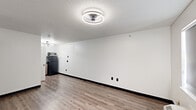 Located at 14255 Northwest Freeway in Houston, TX, this single-floor unit offers a clean, functional layout with a straightforward design. The main living area features wood-look plank flooring throughout, crisp white walls with black baseboards, and a textured ceiling fitted with a modern circular flush-mount light fixture. A wall-mounted PTAC heating and cooling unit provides climate control, and a window allows natural light to filter into the space, keeping the interior bright and open.

The kitchenette area is efficiently designed, featuring warm-toned wood laminate cabinetry with sleek bar-pull hardware and dark countertops. A stainless steel sink, full-size refrigerator, and microwave are included, providing essential amenities in a compact footprint.

The bathroom is a notable highlight, showcasing a bathtub with a full surround clad in large-format marble-patterned tile displaying dramatic grey veining against a white background, lending an elevated aesthetic to the space.

Overall, the unit presents a utilitarian yet updated interior, well-suited for functional everyday use. The consistent wood-look flooring, neutral color palette, and modern fixtures create a cohesive and clean environment throughout.