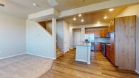 This two-story space is thoughtfully designed with a functional layout that connects living areas seamlessly across both levels. The main floor centers around an open-concept kitchen, which serves as a focal point of the home. Rich, warm-toned wood cabinetry extends to the ceiling, complemented by granite countertops and a matching kitchen island with a built-in sink. Stainless steel appliances, including a refrigerator, range, and microwave, complete the well-equipped kitchen. Light hardwood flooring runs throughout the main level, adding warmth and continuity to the space.

A staircase leads to the upper level, where carpeted bedrooms offer a quieter retreat. Each bedroom features neutral-toned walls and windows fitted with blinds, allowing for natural light and outdoor views of the surrounding neighborhood. The upper level also includes a full bathroom appointed with a granite-topped vanity, a combination tub and shower, and hardwood-style flooring. A generously sized walk-in closet with multi-tiered wire shelving provides ample storage. Additional closet space is accessible near the upper stairwell landing, rounding out the practical storage options throughout the home.