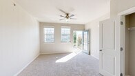 Located in Cottleville, MO, this single-floor home offers four bedrooms, two full bathrooms, and a well-organized layout across a comfortable footprint. The kitchen serves as a central hub, featuring rich dark-wood cabinetry, stainless steel appliances including a refrigerator, range, and microwave, a granite-topped peninsula with an undermount sink, and pendant lighting overhead. Wood-look flooring anchors the kitchen and flows into the bathrooms, while plush carpet covers the living and bedroom areas. Both bathrooms are finished with dark-wood vanity cabinetry, neutral countertops, and full tub-shower combinations with chrome fixtures. The primary bedroom is generously sized, bathed in natural light from multiple windows, and features a ceiling fan and a glass-panel door opening directly to a private balcony with outdoor views. The additional bedrooms are bright and well-proportioned, each with carpet flooring and ceiling fans. The living area is open and airy, with large windows that invite abundant natural light and a second balcony access point. Neutral wall tones and clean white trim throughout lend the home a cohesive, move-in-ready aesthetic. A dedicated closet and hallway complete the functional layout of this well-appointed Cottleville residence.