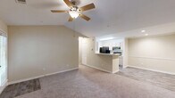 Located at Olde Eastwood Village in Asheville, NC, this 2-bedroom, 2-bathroom single-floor residence offers a comfortable and functional layout with warm neutral tones throughout. The open living room is a standout space, featuring vaulted ceilings, a ceiling fan, plush carpeting, a tile-surround fireplace with a classic white mantle, and a glass door leading to an outdoor area, filling the room with natural light. The kitchen is accessible via a peninsula breakfast bar from the living area, offering ample cabinetry in a light wood finish, generous counter space, and black appliances including a refrigerator, electric range, and dishwasher, with easy-care hardwood-style flooring. A dedicated laundry room with washer and dryer hookups adds everyday convenience. The primary bedroom features vaulted ceilings, a bright window, soft carpeting, and direct access to its own bathroom. The second bedroom is generously sized with a large window offering leafy outdoor views and plush carpet underfoot. Both bathrooms include tub-shower combinations, wood-style flooring, and vanities with ample storage. Two closets and a hallway complete this well-organized layout, creating a practical and inviting home in the heart of Asheville.