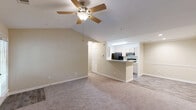 Located at Olde Eastwood Village in Asheville, NC, this 2-bedroom, 2-bathroom single-floor residence offers a comfortable and functional layout with warm neutral tones throughout. The open living room is a standout space, featuring vaulted ceilings, a ceiling fan, plush carpeting, a tile-surround fireplace with a classic white mantle, and a glass door leading to an outdoor area, filling the room with natural light. The kitchen is accessible via a peninsula breakfast bar from the living area, offering ample cabinetry in a light wood finish, generous counter space, and black appliances including a refrigerator, electric range, and dishwasher, with easy-care hardwood-style flooring. A dedicated laundry room with washer and dryer hookups adds everyday convenience. The primary bedroom features vaulted ceilings, a bright window, soft carpeting, and direct access to its own bathroom. The second bedroom is generously sized with a large window offering leafy outdoor views and plush carpet underfoot. Both bathrooms include tub-shower combinations, wood-style flooring, and vanities with ample storage. Two closets and a hallway complete this well-organized layout, creating a practical and inviting home in the heart of Asheville.