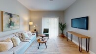Located at 149 Main St in Upton, Massachusetts, this single-floor residence offers a thoughtfully designed layout with quality finishes and a clean, contemporary aesthetic. The living room is a welcoming space with light hardwood flooring, soft neutral wall tones, and a large sliding glass door that fills the room with natural light and provides outdoor views. The area comfortably accommodates seating and entertainment, creating an inviting atmosphere for both relaxing and hosting. The kitchen is well-equipped and visually striking, featuring white shaker-style cabinetry with matte black hardware, granite countertops, a classic subway tile backsplash, and stainless steel appliances including a gas range, microwave, dishwasher, and refrigerator. A kitchen island provides additional prep and dining space. The bedroom is carpeted for comfort, finished in soft gray tones, and includes a bright window that allows natural light to filter in. The bathroom features a white vanity with granite countertop, a large mirror with modern lighting, and a shower-tub combination. Consistent use of neutral tones, natural light, and quality materials throughout the space creates a cohesive and comfortable living environment.