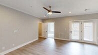 This single-story home in Lynchburg, Virginia offers a clean, modern design with a neutral color palette and quality finishes throughout. The main living area features light-toned hardwood-style flooring, crown molding, recessed lighting, and a ceiling fan, creating a bright and comfortable atmosphere. Natural light flows in through windows fitted with blinds, and an exterior door provides convenient outdoor access.

The kitchen is a standout feature, boasting gray shaker-style cabinetry with matte black hardware, light quartz countertops, a center island with a built-in sink, pendant lighting, and a full suite of stainless steel appliances. A dedicated pantry with built-in shelving adds excellent storage capacity.

The primary bedroom is generously sized with plush carpeting, a large window, and a double-door closet. A spacious walk-in closet with multi-level shelving and hanging rods provides ample organization. The second bedroom also features carpeting and an arched architectural detail, adding a subtle design element.

The bathroom includes a full tub-shower combination with a clean white surround. A utility room and hallway round out the functional layout of this well-designed home.