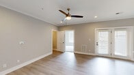 This single-story home in Lynchburg, Virginia offers a clean, modern design with a neutral color palette and quality finishes throughout. The main living area features light-toned hardwood-style flooring, crown molding, recessed lighting, and a ceiling fan, creating a bright and comfortable atmosphere. Natural light flows in through windows fitted with blinds, and an exterior door provides convenient outdoor access.

The kitchen is a standout feature, boasting gray shaker-style cabinetry with matte black hardware, light quartz countertops, a center island with a built-in sink, pendant lighting, and a full suite of stainless steel appliances. A dedicated pantry with built-in shelving adds excellent storage capacity.

The primary bedroom is generously sized with plush carpeting, a large window, and a double-door closet. A spacious walk-in closet with multi-level shelving and hanging rods provides ample organization. The second bedroom also features carpeting and an arched architectural detail, adding a subtle design element.

The bathroom includes a full tub-shower combination with a clean white surround. A utility room and hallway round out the functional layout of this well-designed home.