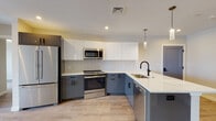 Located at 125 Warren St in Boston's Roxbury neighborhood, this thoughtfully designed single-floor residence showcases modern finishes and a clean, contemporary aesthetic throughout. The open-concept kitchen is a standout feature, outfitted with two-tone cabinetry — crisp white upper cabinets paired with slate-gray lowers — complemented by a subway tile backsplash, quartz countertops, stainless steel appliances, and a peninsula with an undermount sink and matte black fixtures. Light wood-style flooring runs throughout the living areas, contributing to a warm and cohesive feel. The generously sized living area benefits from natural light streaming through double-hung windows, with views of the surrounding neighborhood and Boston's skyline visible in the distance. The bedrooms are bright and open, each featuring multiple windows and light-toned walls that enhance the sense of space. The bathrooms are finished to a high standard, each featuring large-format tile flooring, marble-look walk-in glass-enclosed showers with matte black hardware, white vanities with quartz countertops, and recessed lighting. A convenient half bath with tile flooring and matching cabinetry provides additional functionality. Recessed lighting and matte black accents are carried consistently throughout, lending the space a polished, unified design sensibility.