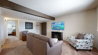 Located at 3330 SW Eveningside Dr in Topeka, Kansas, this single-story home offers three bedrooms and one bathroom within a efficiently designed floor plan. The living room is a comfortable, carpeted space highlighted by a decorative exposed beam on the ceiling, a built-in electric fireplace, and a window that brings in natural light. It connects seamlessly to the dining area, which features a ceiling fan with light fixture and its own window, creating a bright and functional everyday living space. A breakfast bar separates the dining area from the kitchen, which is equipped with light wood cabinetry, laminate countertops, a white electric range with overhead ventilation, and tile flooring. The full bathroom includes a wooden vanity with a wide countertop, a large mirror, and tile flooring, with a walk-in closet conveniently accessible nearby. The primary bedroom is a generously sized, carpeted retreat with a ceiling fan, window, and ample closet space. The two additional bedrooms are also carpeted and include closets, making them well-suited for various uses. Throughout the home, neutral tones and consistent finishes create a cohesive and move-in-ready atmosphere.