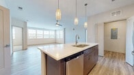 Located at 9253 Old Union Rd in Union, Kentucky, this well-appointed 2-bedroom, 2-bathroom residence offers a thoughtfully designed single-level floor plan with generous living space throughout. The open-concept kitchen and living area serves as the heart of the home, showcasing a large center island with a white quartz countertop, an undermount sink, and a stainless steel dishwasher. Elegant pendant lights hang above the island, complementing the full suite of stainless steel appliances, including a French door refrigerator, electric range, and over-the-range microwave. Light-toned cabinetry extends to the ceiling, paired with a classic white subway tile backsplash for a clean, modern aesthetic. Light luxury vinyl plank flooring runs throughout the main living areas, while a ceiling fan anchors the spacious living room, which is bathed in natural light from a bank of large windows with outdoor views. Both bedrooms are well-sized and feature plush carpeting, ceiling fans, and closets. The primary bedroom connects to a private bathroom with wood-toned cabinetry, a white quartz vanity, and a tiled walk-in shower with sliding glass doors, plus an adjacent walk-in closet with built-in shelving. A dedicated laundry area and a utility space housing the water heater and electrical panel round out the functional layout of this modern residence.