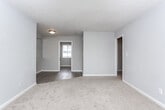 Located at 100 Lockwood Ct in Columbus, Georgia, this single-floor home offers a straightforward, functional layout with clean, neutral finishes throughout. The living area features a combination of plush carpet and wood-look vinyl flooring, with natural light streaming in through slatted blinds. A large mirrored wall panel adds depth and brightness to the space, while a ceiling fan with integrated lighting provides comfort and illumination.

The kitchen is well-appointed with granite countertops and a matching backsplash, white cabinetry with modern matte black hardware, and a full suite of white appliances including a refrigerator, electric range, and over-the-range microwave. The wood-look flooring continues seamlessly into this area, tying the space together.

The bedroom is comfortably sized with soft carpet underfoot, a ceiling fan with lighting, and a window that invites natural light. A dedicated closet space provides practical storage.

The bathroom is finished with a granite-topped white vanity, wood-look tile flooring, and a full tub and shower combination with white tile surround. A window above the tub adds ventilation and light. Throughout the home, gray-toned walls and white trim create a cohesive, move-in-ready aesthetic.
