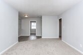 Located at 100 Lockwood Ct in Columbus, Georgia, this single-floor home offers a straightforward, functional layout with clean, neutral finishes throughout. The living area features a combination of plush carpet and wood-look vinyl flooring, with natural light streaming in through slatted blinds. A large mirrored wall panel adds depth and brightness to the space, while a ceiling fan with integrated lighting provides comfort and illumination.

The kitchen is well-appointed with granite countertops and a matching backsplash, white cabinetry with modern matte black hardware, and a full suite of white appliances including a refrigerator, electric range, and over-the-range microwave. The wood-look flooring continues seamlessly into this area, tying the space together.

The bedroom is comfortably sized with soft carpet underfoot, a ceiling fan with lighting, and a window that invites natural light. A dedicated closet space provides practical storage.

The bathroom is finished with a granite-topped white vanity, wood-look tile flooring, and a full tub and shower combination with white tile surround. A window above the tub adds ventilation and light. Throughout the home, gray-toned walls and white trim create a cohesive, move-in-ready aesthetic.