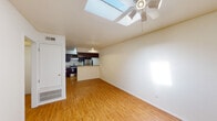 This single-floor unit offers a well-organized and functional layout that seamlessly connects the main living area to the kitchen. The open-concept living space is immediately distinguished by a prominent skylight that floods the room with natural light, complemented by a ceiling fan with integrated lighting. Warm-toned hardwood-style flooring runs consistently throughout the entire unit, creating a cohesive and inviting atmosphere.

The kitchen is designed for practicality, featuring rich dark-wood cabinetry, a peninsula counter that defines the boundary between the kitchen and living area, stainless steel appliances including a refrigerator and electric range, a built-in microwave, and a stainless steel sink. Ample upper cabinet storage ensures functional use of the available space.

The bedrooms are well-proportioned, each equipped with ceiling fans and windows fitted with blinds that allow for natural light and privacy. The rooms offer a clean, neutral palette that adapts easily to a variety of uses.

The bathroom is finished with a full tub-and-shower combination with white tile surround, a wood-tone vanity with a light countertop, and brushed nickel fixtures. The hardwood-style flooring extends into this space, maintaining design continuity throughout the unit. Additional storage closets are accessible near the kitchen entry area.