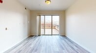 Located at 2120 S Highland Dr in Salt Lake City, Utah, this one-bedroom, two-bathroom residence is housed within a distinctive multi-story brick building that blends classic architectural character with modern interior finishes. Light-toned hardwood-style flooring flows throughout the single-level layout, complementing the clean, neutral color palette found in every room.

The open-concept kitchen and living area serves as the heart of the home. The kitchen features a large peninsula island with a white quartz countertop, an undermount sink with a matte black faucet, dark espresso cabinetry, and a full suite of stainless steel appliances including a refrigerator, range, microwave, and dishwasher. Stylish pendant lighting hangs above the island, adding warmth to the space. The adjacent living area is bright and open, leading to a set of sliding glass doors that open onto a private outdoor terrace with views of the surrounding neighborhood.

The bedroom is a well-proportioned retreat, offering a calm atmosphere with neutral walls and durable flooring. It is complemented by a generous walk-in closet outfitted with built-in shelving and a hanging rod. Both bathrooms are finished with dark vanity cabinetry, white quartz countertops, and brushed nickel fixtures, maintaining a consistent and polished aesthetic throughout the residence.