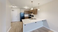 Located at 1455 Castle Manor Dr in Lincoln, Illinois, this single-floor, 2-bedroom, 1-bathroom residence offers a practical and comfortable layout. The open-concept kitchen and living area serves as the heart of the home, featuring warm-toned cabinetry, white countertops, a peninsula with an integrated double sink and pendant lighting overhead, and black appliances including a refrigerator, range, microwave, and dishwasher. Light wood-style flooring runs throughout the main living space, complementing the bright, neutral color palette. A ceiling fan in the living area adds to the comfortable ambiance, while a window brings in natural light.

Both bedrooms are carpeted and feature ceiling fans, windows with blinds for natural light and privacy, and access to closets. The primary bedroom offers a generous footprint with two doorways providing convenient access. The full bathroom is equipped with a tub-shower combination, brushed nickel grab bars, and wood-style flooring. Additional practical spaces include a pantry, a utility room, a hallway, and five closets distributed throughout, ensuring abundant storage. The clean, neutral finishes and thoughtful layout make this a functional and inviting residence.
