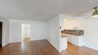 Located at 2020 W Alameda Ave in Anaheim, CA, this one-bedroom, one-bathroom unit offers a well-organized single-floor layout with a practical and comfortable flow throughout. The open living area is bright and spacious, featuring wood-style flooring, crisp white walls, and a textured ceiling. Large windows dressed with vertical blinds allow generous natural light to fill the space, while a ceiling fan adds comfort overhead. A wall-mounted AC unit provides additional climate control. The kitchen is positioned adjacent to the living area and features white cabinetry, granite-style countertops, a mosaic tile backsplash, and a peninsula that creates a natural divide between the cooking and living spaces. A tall pantry cabinet and upper cabinetry provide ample storage. The bedroom offers plush carpeting, a walk-in closet with built-in shelving rods, and direct access to the full bathroom. The bathroom is well-appointed with a tub/shower combo, a curved curtain rod, a vanity with a stone-style countertop, and a bright window above the tub. Two closets—including a dedicated walk-in—offer excellent storage. A connecting hallway ties all rooms together efficiently, making this a functional and well-designed living space.