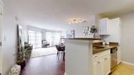 This single-floor residence at 900 Crest On in Fort Lee, New Jersey offers a thoughtfully designed open-concept layout that seamlessly connects the kitchen, dining, and living areas. Rich hardwood flooring runs throughout the main living spaces, lending warmth and visual continuity across the floor plan.

The kitchen is outfitted with white cabinetry, dark granite countertops, a white subway tile backsplash, and stainless steel appliances including a gas range, built-in microwave, refrigerator, and dishwasher. Light tile flooring and a peninsula with breakfast bar seating connect the kitchen to the dining and living areas.

The living room is bright and inviting, benefiting from large sliding glass doors that open onto a private balcony, as well as an additional window that fills the space with natural light and views of the surrounding area. The dining space sits adjacent, comfortably accommodating a full dining set.

The bedroom is a calm, carpeted retreat featuring a generously sized window with outdoor views and ample space for furnishings. The bathroom includes a white vanity with a large mirror, tile flooring, and a clean, neutral palette. Overall, the residence presents a comfortable and functional living environment in a well-located Fort Lee community.