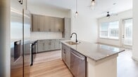Located at 3108 McGinnis Ferry Rd in Suwanee, GA, this single-floor residence offers a thoughtfully designed layout that maximizes every square foot. The open-concept living, dining, and kitchen area serves as the heart of the home, with light hardwood-style flooring, bright white walls, and natural light streaming through large windows. A ceiling fan anchors the living space, adding both function and comfort.

The kitchen is a standout, featuring gray shaker-style cabinetry with matte black hardware, granite countertops, a classic white subway tile backsplash, and a central island with a undermount sink and stainless steel dishwasher. Stainless steel appliances, including a range with over-the-range microwave and refrigerator, complete the space. Elegant globe pendant lights hang above the island, adding a modern touch.

The bedroom offers plush carpeting, a natural light source from a dedicated window, and a striking slate-blue accent wall with vertical board-and-batten detailing. The full bathroom features blue-gray shaker vanity cabinetry, granite countertops, matte black fixtures, and direct access to a walk-in closet with built-in shelving. A dedicated laundry area rounds out this efficient and stylish home.