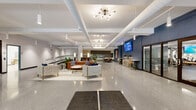 Located in the heart of downtown Syracuse at 101 S Salina St, this thoughtfully designed single-floor commercial space combines contemporary aesthetics with functional versatility. The entrance welcomes visitors with large street-facing windows that flood the vestibule with natural light, complemented by polished terrazzo flooring that extends throughout the entire space.

The expansive open lobby serves as the centerpiece, featuring a curated lounge area with tufted velvet seating, leather sofas, and elegant gold-accented furniture arranged on plush area rugs. A striking sputnik chandelier anchors the ceiling alongside exposed white ductwork that adds an industrial-modern character. Bold navy blue accent walls provide a dramatic backdrop for a wall-mounted display screen and bar-height counter seating, creating a casual gathering zone ideal for collaboration.

Glass-partitioned rooms along the perimeter offer semi-private spaces, including a well-equipped kitchen area featuring blue subway tile, open shelving, and modern cabinetry. Additional utility rooms with durable flooring and secure storage provide practical support functions. A separate workspace area, accessible through glass-panel doors, opens into a bright, open-plan work environment. The overall ambiance is polished and professional, balancing an inviting, community-oriented atmosphere with the functionality demands of a dynamic commercial setting.
