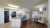 This single-floor residence offers a thoughtfully designed layout that balances comfort and functionality. The living room serves as the heart of the home, featuring wood-look flooring, a ceiling fan, and a large window dressed in teal sheer curtains that invite natural light and provide pleasant outdoor views. The space flows seamlessly into a dedicated dining area, creating an open and connected feel throughout the common areas.

The kitchen is outfitted with white cabinetry, granite countertops, and black appliances, including a range, microwave, and refrigerator. A peninsula with seating for two adds a casual dining option and enhances the kitchen's functionality. The adjacent dining area comfortably accommodates a round table, making it ideal for everyday meals or entertaining.

Both bedrooms are carpeted and generously proportioned, each featuring natural light from windows and ample closet space with louvered bifold doors. The rooms offer a calm, neutral palette that contributes to a restful atmosphere.

Two full bathrooms mirror each other in design, each featuring white vanity cabinetry, granite countertops, large mirrors, and shower-tub combinations. Wood-look flooring in both bathrooms maintains a cohesive aesthetic throughout the residence. Overall, the space presents a clean, contemporary style with consistent finishes across every room.