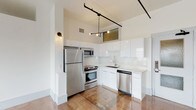 Located in the heart of Downtown Los Angeles, this single-floor unit at 560 S Los Angeles St offers a thoughtfully designed urban living space with modern finishes throughout. The kitchen is a standout feature, outfitted with glossy white cabinetry, stainless steel appliances including a refrigerator, range, microwave, and dishwasher, complemented by a clean white tile backsplash and elegant marble-veined countertops. Industrial-style track lighting with exposed black rails adds a contemporary edge overhead, while polished large-format tile flooring runs seamlessly throughout the main living areas, reflecting light and contributing to a bright, open atmosphere. The living area is generously proportioned, with tall ceilings and a bank of large windows fitted with roller shades that frame sweeping city views of the Downtown Los Angeles skyline. The bathroom is finished with classic white penny tile flooring, a clean white vanity, and a full tub-shower combination enclosed by white subway tile, maintaining a crisp and minimalist aesthetic. The overall ambiance of the space is clean, modern, and urban, making it well-suited for those seeking a contemporary lifestyle in one of Los Angeles's most dynamic and accessible neighborhoods.
