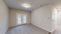Located at 2308 Holiday Loop in Reidsville, NC, this 2-bedroom, 3-bathroom single-floor home offers a well-designed layout with a clean, modern aesthetic throughout. The open-concept living, dining, and kitchen area serves as the heart of the home, finished with durable wood-look plank flooring. The kitchen is outfitted with crisp white shaker-style cabinetry, granite countertops, a peninsula with an integrated sink, and a full suite of stainless steel appliances including a refrigerator, range, and microwave. The living area features soft carpeting and a set of glass French doors that open to a private balcony, allowing natural light to fill the space. The spacious primary bedroom includes a ceiling fan, plush carpet, and direct access to an en-suite bathroom featuring granite-topped vanity with white cabinetry. Two additional bathrooms serve the home, each finished with consistent granite and white cabinetry details. The second bedroom is generously sized with carpeted flooring and easy hallway access. Three closets provide ample storage throughout, and a dedicated laundry area adds everyday convenience. Neutral tones and consistent finishes create a cohesive, move-in-ready environment.